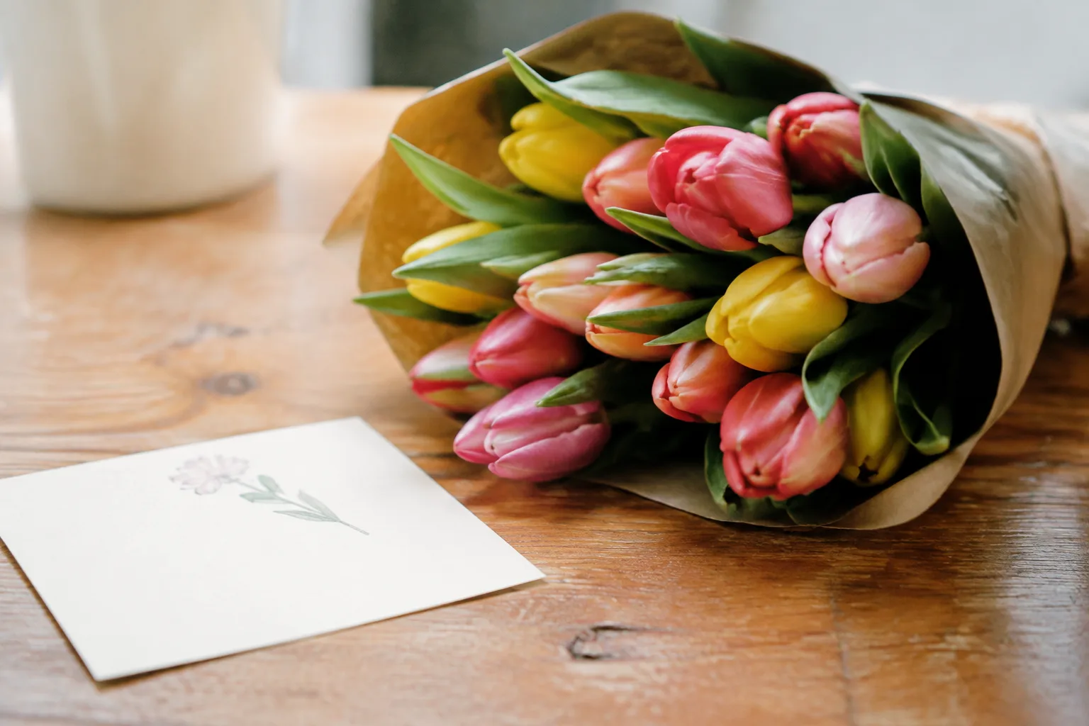 Carte manuscrite posee pres d'un bouquet de tulipes