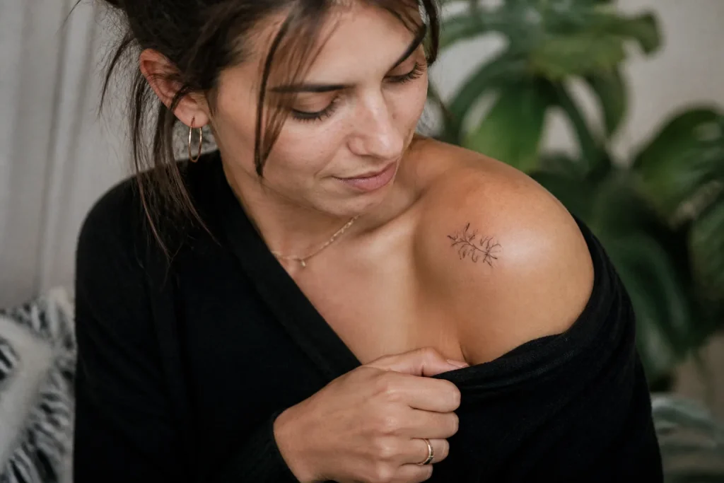 Femme montrant un petit tatouage floral sur son epaule