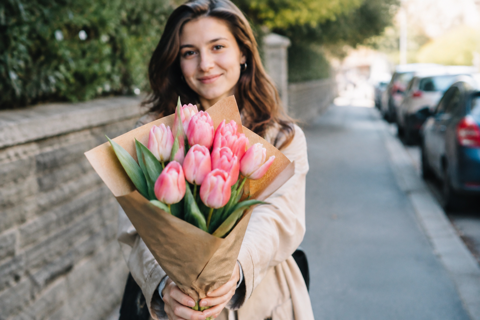 Une fille debout tend un bouquet de tulipes roses