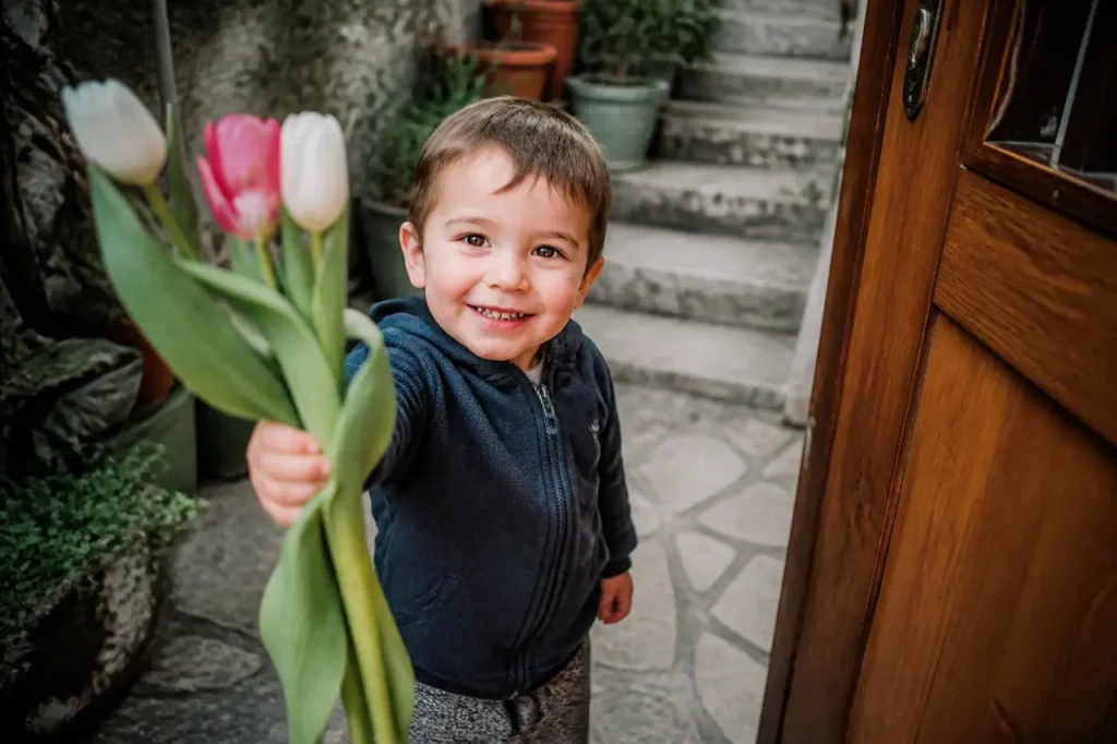 Petit garcon souriant tendant un bouquet de tulipes