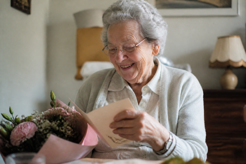 Mamie souriante lisant une carte manuscrite avec des fleurs